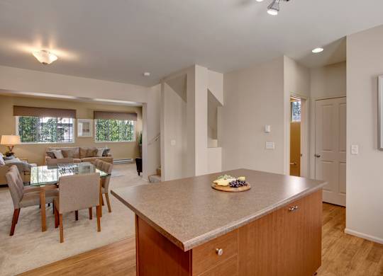 A kitchen with a table and chairs in the foreground and a living room in the background.