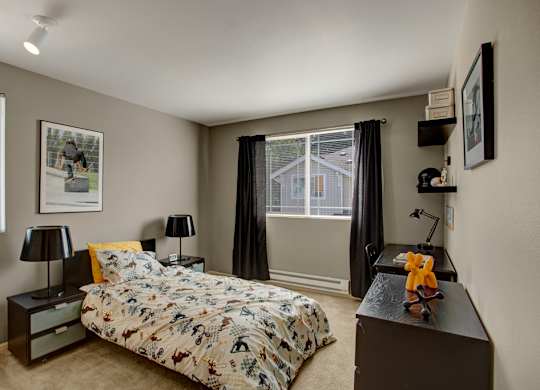 A bedroom with a bed, nightstand, and a window with curtains.