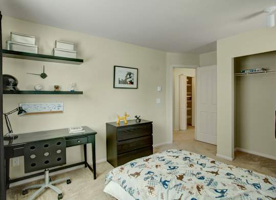 A bedroom with a bed, desk, and shelves.