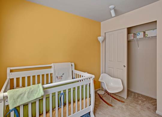 A baby's room with a white crib and a white rocking chair.