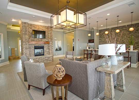 A living room with a stone fireplace and a grey couch.