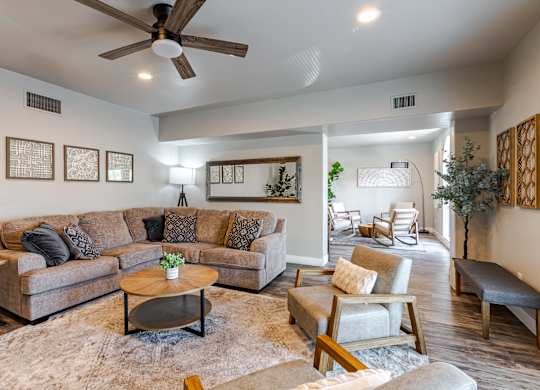 A living room with a brown couch, a coffee table, and a ceiling fan.
