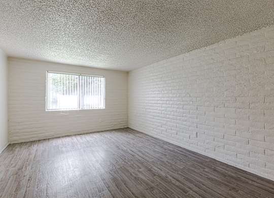 A room with a window and a brick wall.