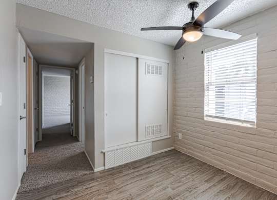 A room with a ceiling fan and a window with blinds.