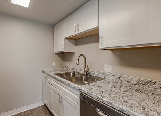 A kitchen with a marble countertop and white cabinets.