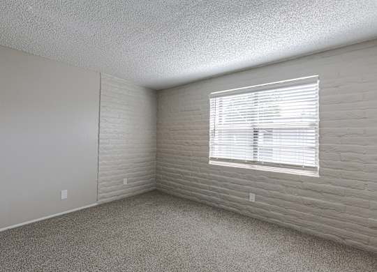 A room with a window covered by white blinds.