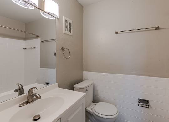 A white bathroom with a toilet, sink, and mirror.