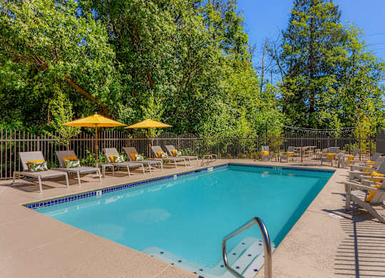 A swimming pool surrounded by yellow chairs and umbrellas.