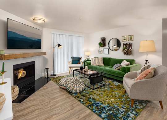 A living room with a fireplace, a green couch, and a painting on the wall.