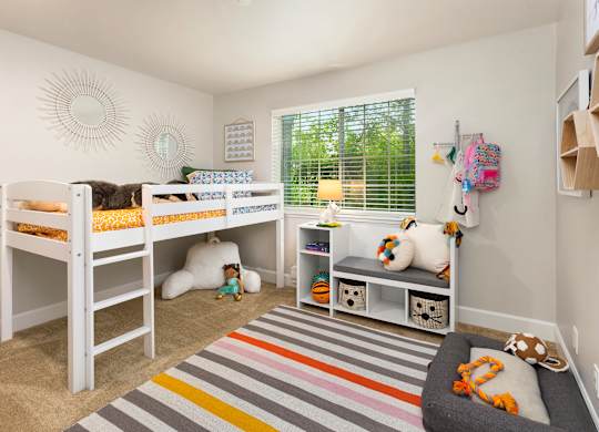 A room with two bunk beds and a bench with toys on it.