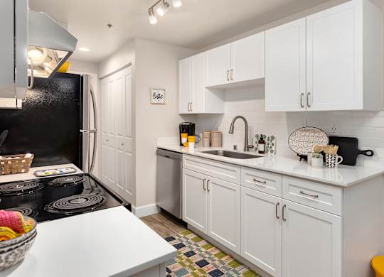 A kitchen with white cabinets and a black refrigerator.