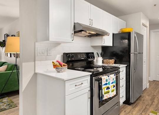 A modern kitchen with white cabinets and a black stove top oven.