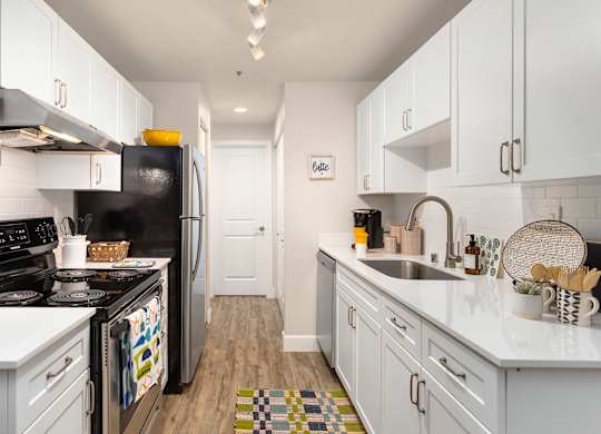 A kitchen with white cabinets and a black refrigerator.