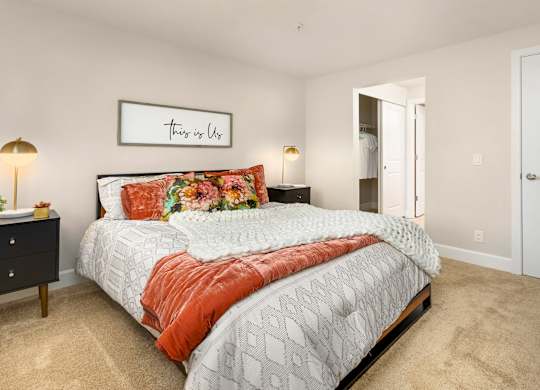 A bedroom with a bed, nightstands, and a framed picture on the wall.