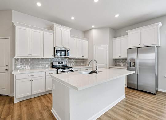 A kitchen with white cabinets and a white island.