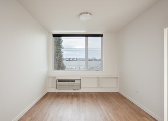an empty living room with a large window and wooden floors