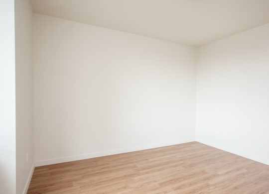 an empty room with wood floors and white walls