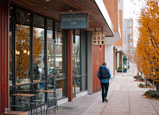 a man walking down a sidewalk in front of a bar