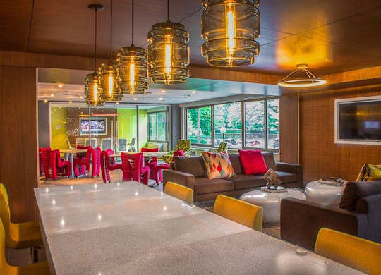 A modern dining area with a long table and colorful chairs.