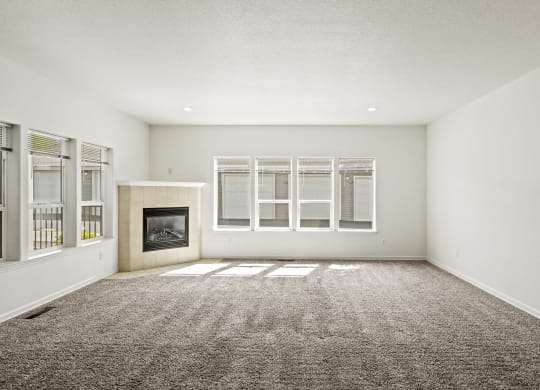 an empty living room with a fireplace and windows