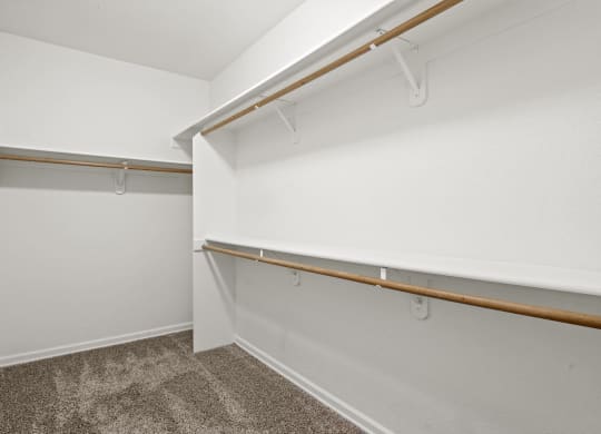 a spacious walk in closet with white walls and carpet