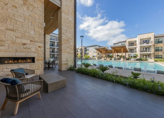Lenox SoCo Apartments  patio with chairs and a fireplace next to a pool