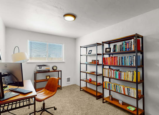 a home office with a bookshelf and a desk with a computer