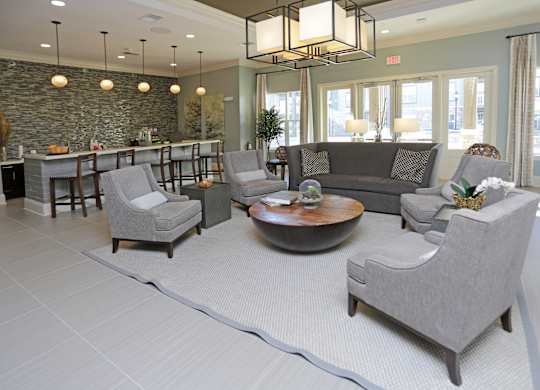 A living room with grey chairs and a stone wall.