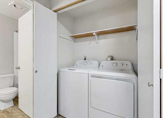 A white laundry room with a toilet and a washer and dryer.