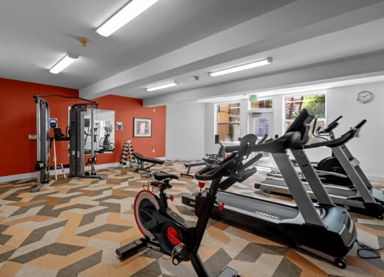 a gym with treadmills and other exercise equipment in a room with red walls