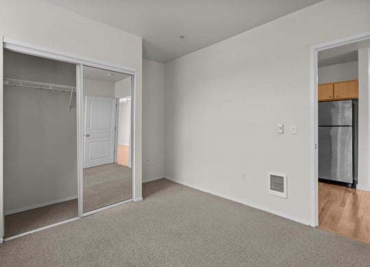 Bedroom with mirrored closet doors and white walls at Collins Circle apartments in the Goose Hollow district in Portland, Oregon.