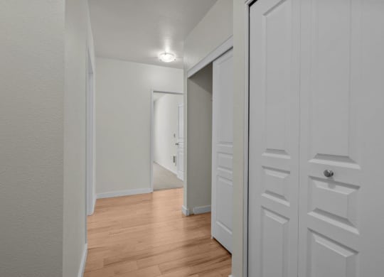 Hallway view with white walls and wood-style flooring at Collins Circle apartments in the Goose Hollow district in Portland, Oregon.
