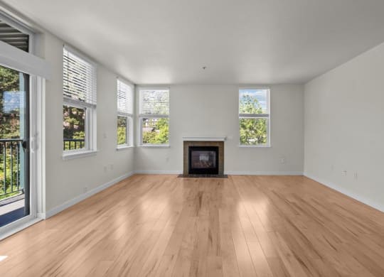 Living room with large windows, wood-style flooring, and fireplace at Collins Circle apartments in the Goose Hollow district in Portland, Oregon.
