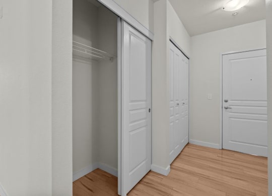 Bedroom with wood-style floors, white walls, and spacious double closets at Collins Circle apartments in the Goose Hollow district in Portland, Oregon.