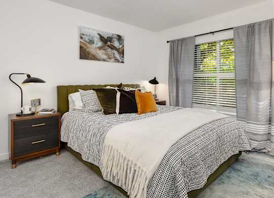 A bedroom with a bed, nightstand, and a painting on the wall.