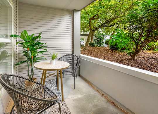 A patio with a chair, table, and potted plant.