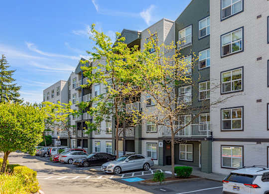 A row of modern apartment buildings with cars parked in front.