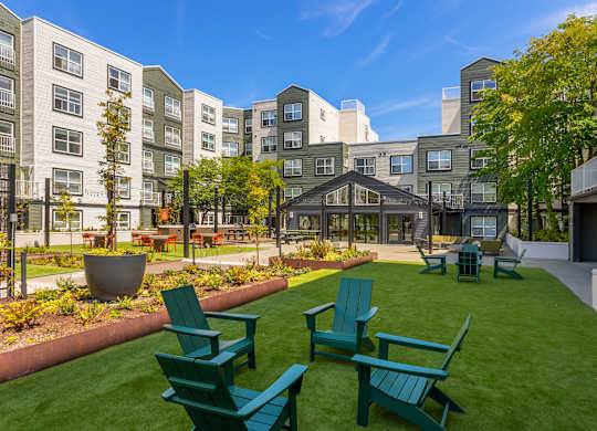 A sunny day at a green and white apartment complex with a grassy courtyard.