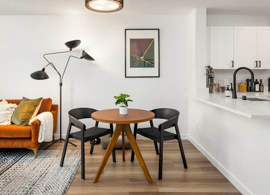 A living room with a brown table and chairs, a couch, and a framed picture on the wall.