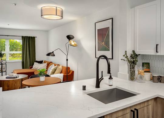 A modern kitchen with a marble countertop and a large window with green curtains.