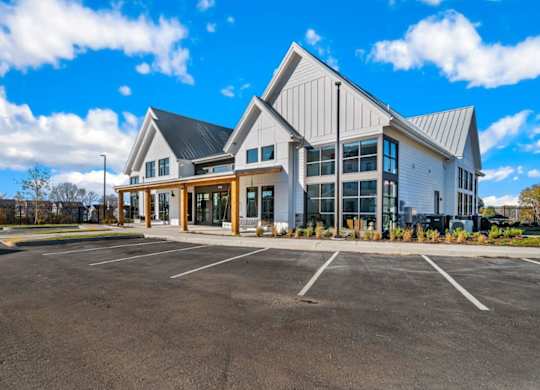 A large white building with a black roof and a parking lot in front.