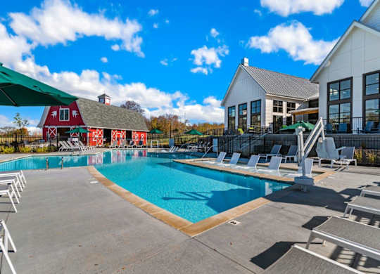 A large swimming pool with lounge chairs and a white building in the background.