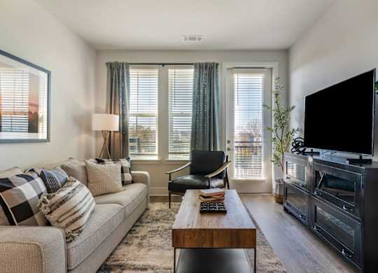 A living room with a couch, a chair, a coffee table, and a television.