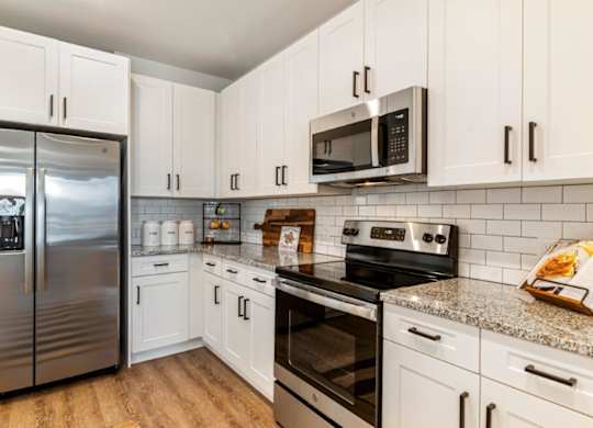 A kitchen with white cabinets and a stainless steel refrigerator.
