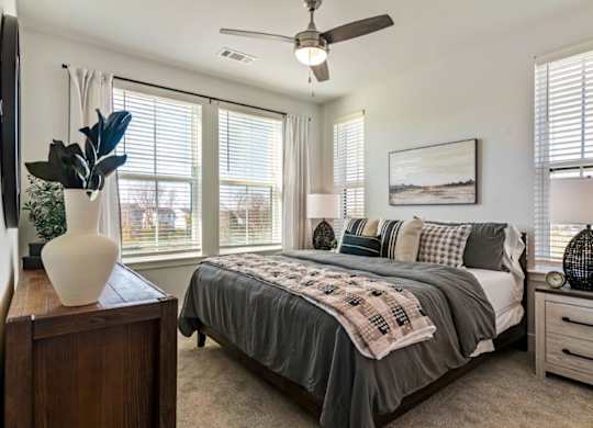 A bedroom with a bed, a dresser, and a ceiling fan.