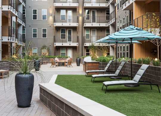 A patio with chairs and a vase is surrounded by apartment buildings.