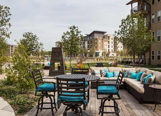 A patio with a table and chairs is surrounded by trees and buildings.