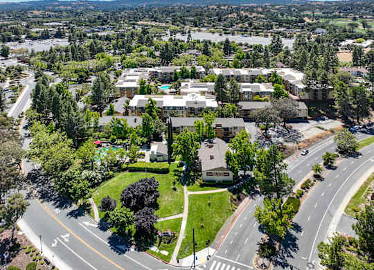A bird's eye view of a residential area with houses, trees, and roads.
