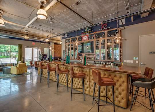 A bar with a row of stools in front of it. at Discovery at The Realm, Lewisville, TX