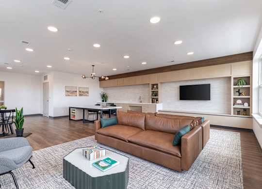 A living room with a brown leather couch and a grey armchair.